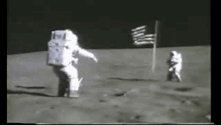Zwei Astronauten und eine Amerikanische Flagge auf dem Mond. Ein Soldat springt in die Luft und salutiert im Sprung vor der Amerikanischen Flagge. Der Soldat ist im Vergleich zur Erde relativ lange in der Luft, bevor seine Füße wieder die Mondoberfläche berühren.