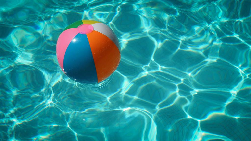 Ein Wasserball mit bunten Streifen schwimmt auf einer Wasseroberfläche.