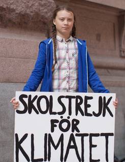 Greta Thunberg steht mit einem Schild vor dem Parlament in Schweden. Auf  dem Schild steht auf Schwedisch: Schulstreik für das Klima!