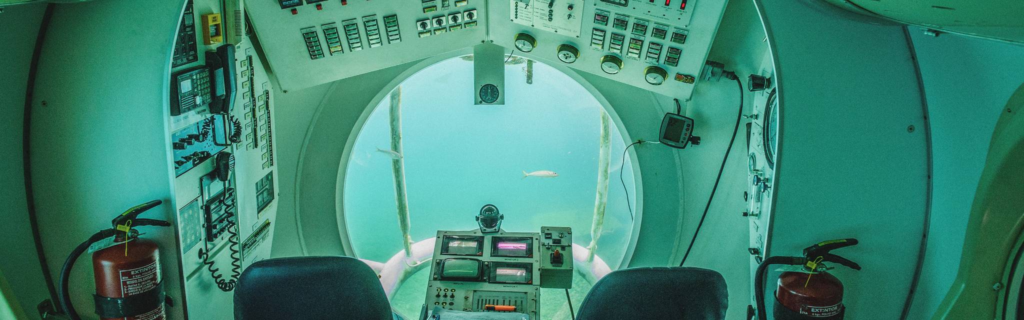 Innenansicht eines U-Boots. Durch ein Fenster sind Fische zu sehen.