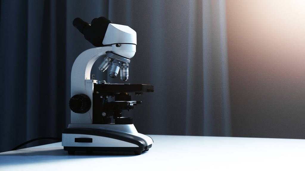 Ein Mikroskop steht auf einer weißen Tischfläche.