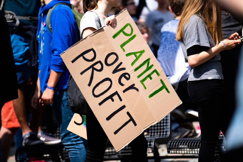 Auf einem Pappschild steht: Planet over profit.