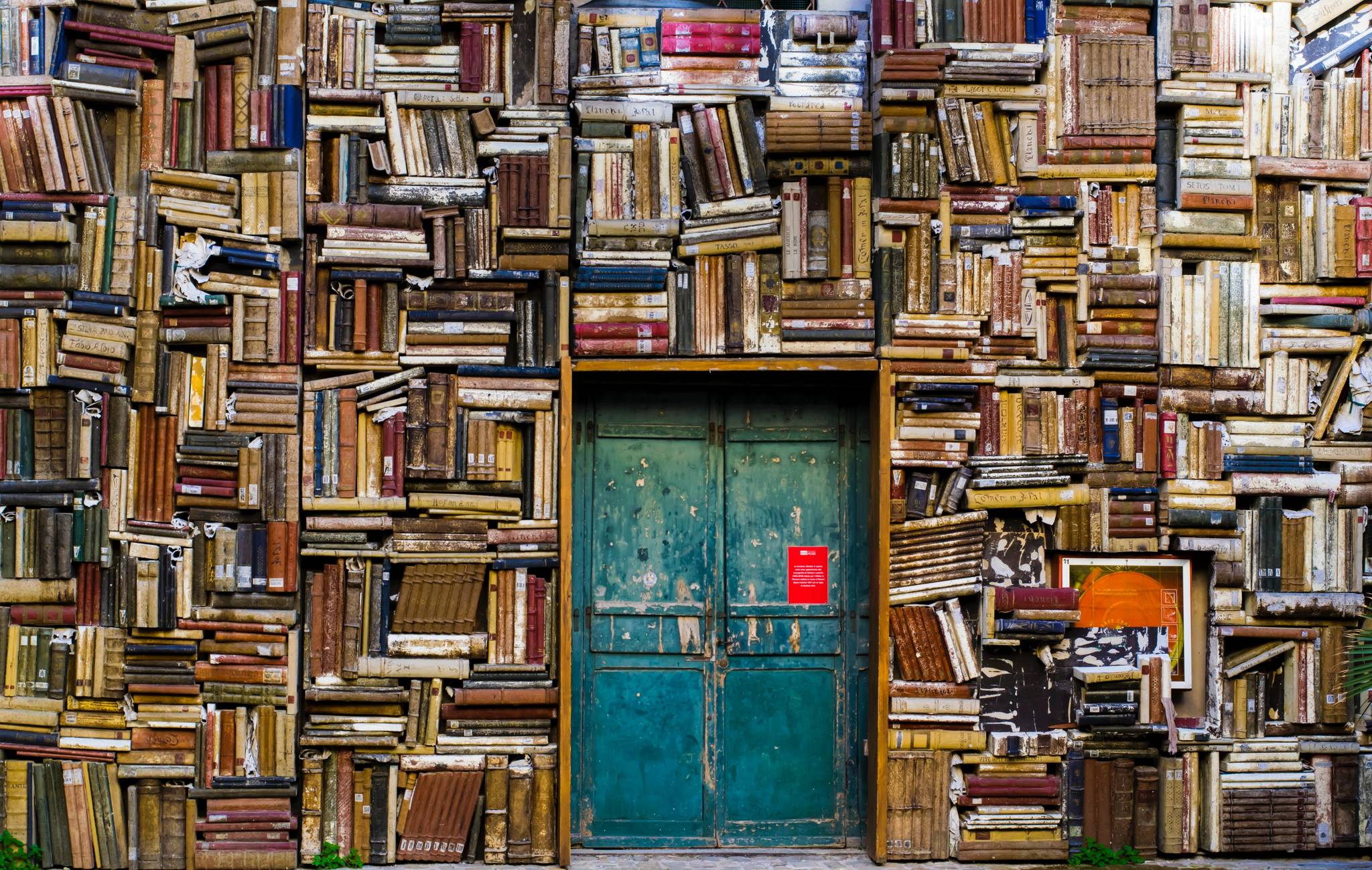 Eine Wand aus Büchern umgibt eine alte Holztüre